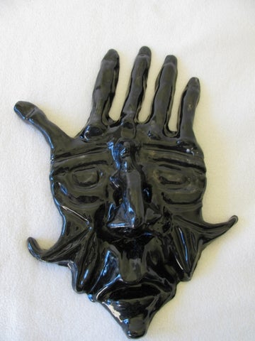 A hand with a face in the middle glazed in black