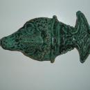 A mask in the shape of a fish when turned sideways, and a human face when turned right side up. Glazed with green glaze.