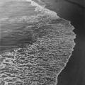 wave coming over wet sand. Black-and-white handmade silver gelatin print 